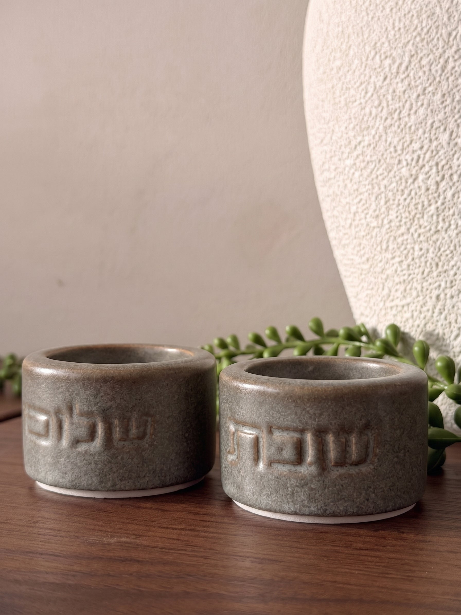 זוג פמוטי שבת עגולים מחרס בגוון אבן-חום גרניט עם גימור מט, חרוטים במילים "שבת" ו"שלום" בפונט מודרני