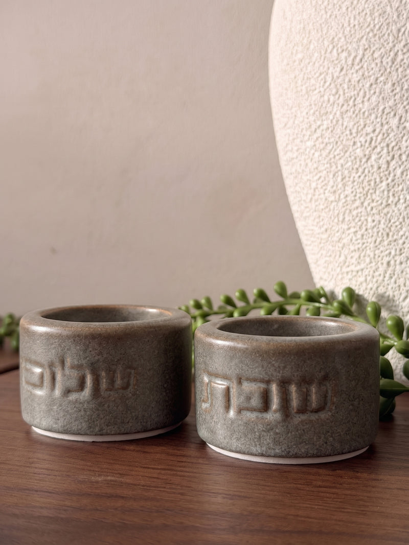 זוג פמוטי שבת עגולים מחרס בגוון אבן-חום גרניט עם גימור מט, חרוטים במילים "שבת" ו"שלום" בפונט מודרני