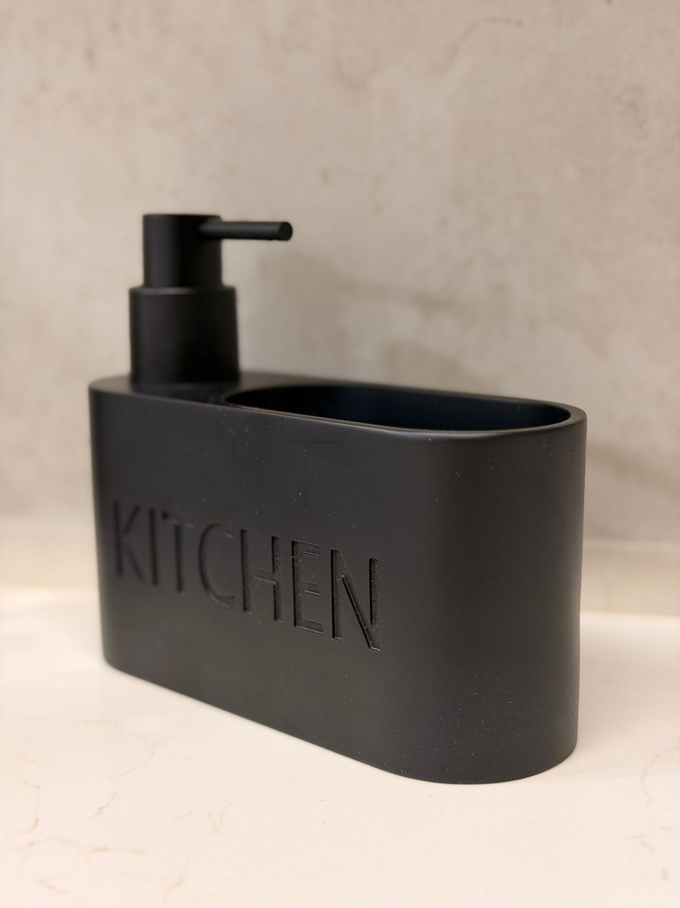 דיספנסר שחור מט מעוגל למטבח עם כיתוב KITCHEN, כולל מיכל סבון ותא לספוג או מברשת, עיצוב מודרני ונקי