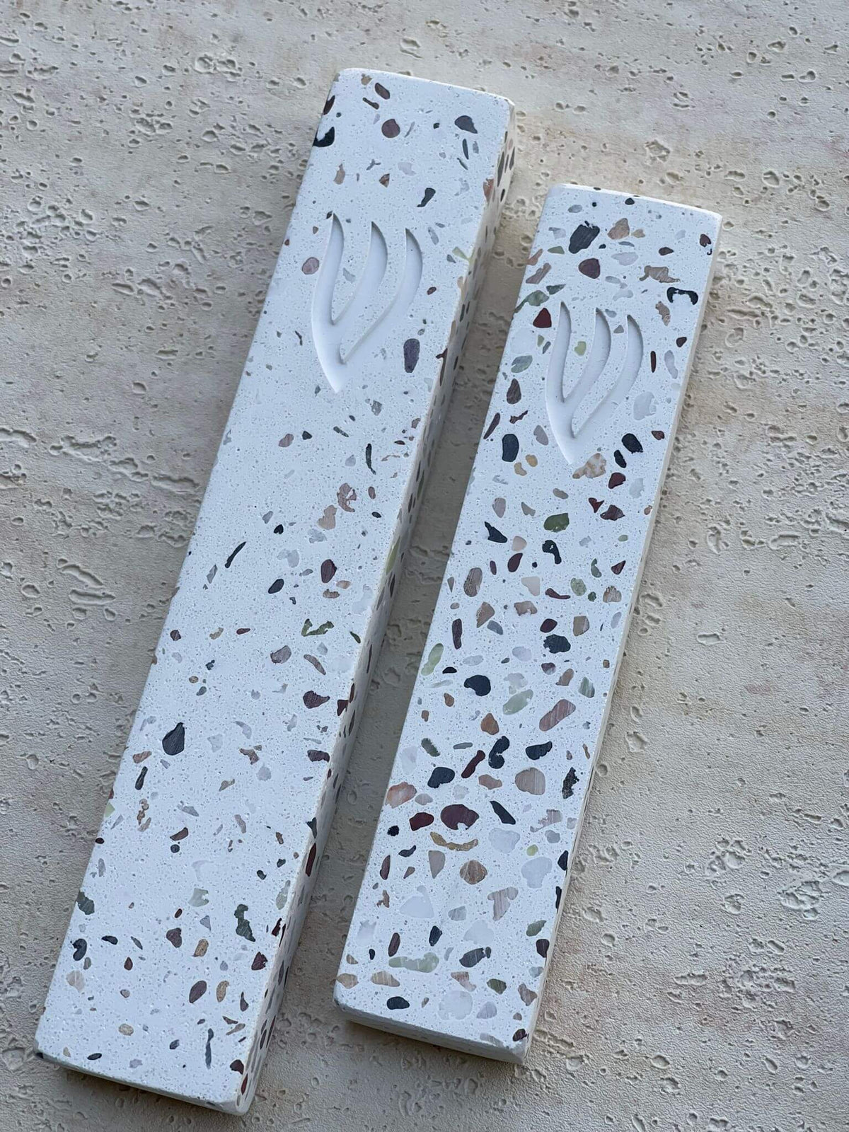 בית מזוזה מבטון טראצו בעיצוב מודרני עם דוגמת אבן צבעונית על רקע לבן וחריטת האות ש׳