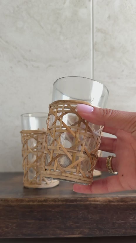 כוס זכוכית דקורטיבית עטופה קליעת ראטן טבעית מוחזקת ביד