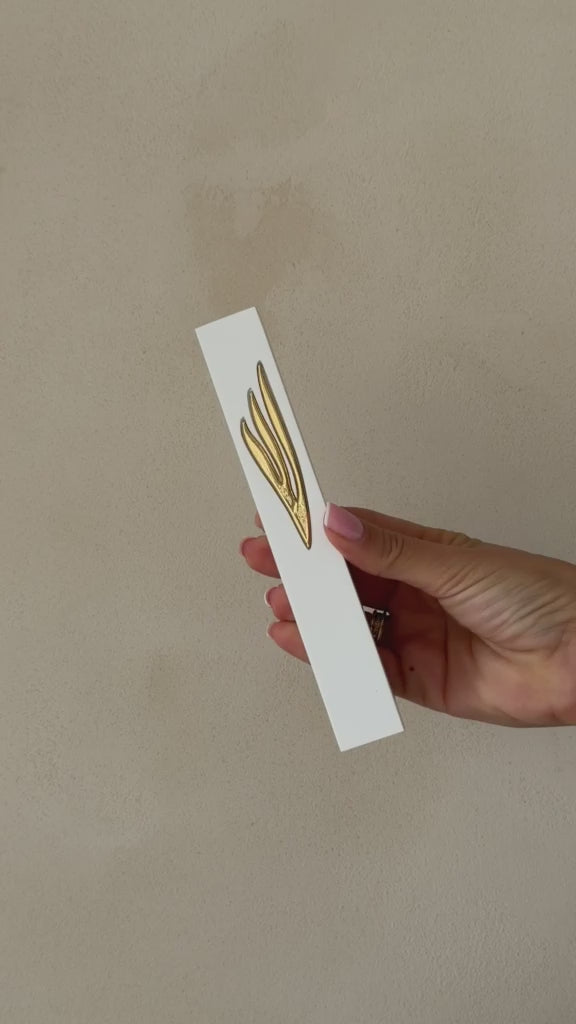 בית מזוזה לבן עם עיטור שין מוזהב מוארך מוחזק ביד