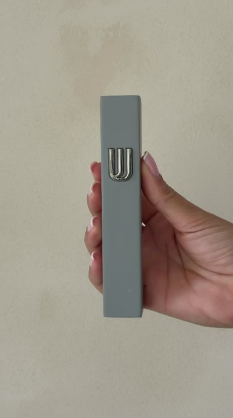 בית מזוזה אפור עם עיטור שין כסוף בולט בחלק העליון