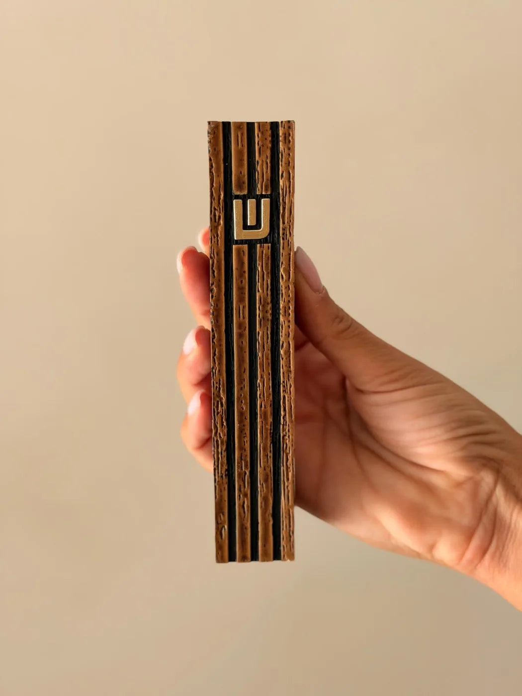 בית מזוזה רידג' בגימור עץ עם פסים שחורים ואות למ"ד מוזהבת - מבט חזיתי מלא ביד